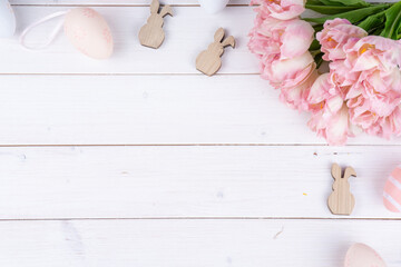 Ostern Bild mit Textfreifläche - Osterhasen, Eier und Blumen auf einem Holzhintergrund. 