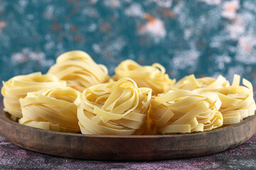 Raw pasta nests on wooden marble plate