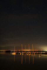 Langzeitbelichtung mit Sternenhimmel und Spiegelung im Wasser am Hafen