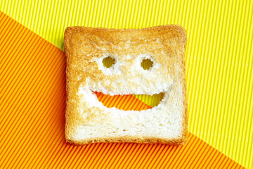 Smiling bread toast on a yellow and orange striped background. Good mood, positive emotions, joy, happiness, good morning, delicious breakfast