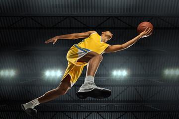 Young professional basketball player in action, motion isolated on black background, look from the bottom. Concept of sport, movement, energy and dynamic, healthy lifestyle. Training, practicing.
