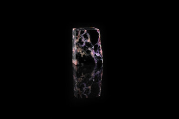 Natural mineral stone - polished charoite gemstone on black glass background.