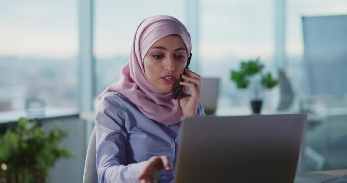 Arabic young formal businesswoman talking business talk in corporate office working in call center using laptop computer.