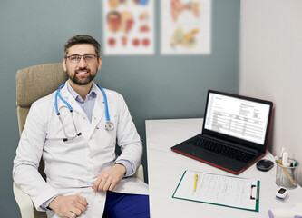 Experienced doctor sitting at his workplace wearing a medical coat while analysis of patient's medical record