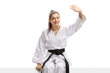 Woman in karate kimono sitting on a panel and waving © Ljupco Smokovski