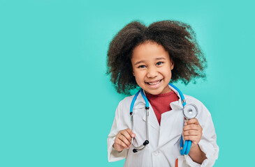 Portrait of positive African American female kid wearing a doctor coat with phonendoscope, standing...
