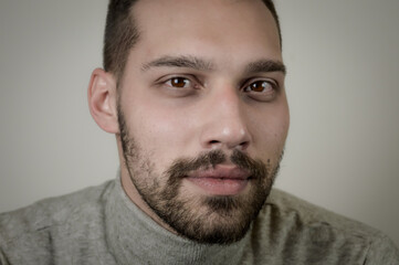 Obraz premium Portrait of a young brown-haired man with a short beard and a gray turtleneck sweater