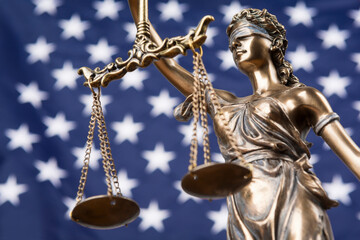 The statue of justice Themis or Justitia, the blindfolded goddess of justice against the flag of the United States of America, as a legal concept