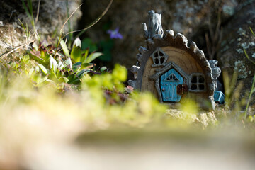 tiny house like a hobbit home with blue door and chimney in the middle of the forest