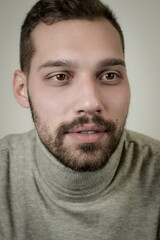 Fototapeta premium Portrait of a young brown-haired man with a short beard and a gray turtleneck sweater 