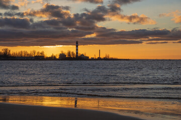 Naklejka premium View to the Daugavgriva lighthouse from Mangalsala pier against colorful sunset sky