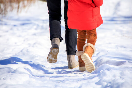 Boots of a mother and daughter walking in the snow