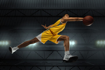Young professional basketball player in action, motion isolated on black background, look from the...