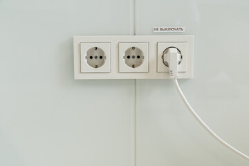 several plastic socket, white, mounted on a gray wall. one outlet in use