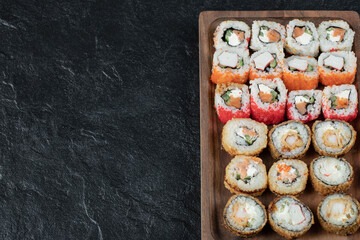 Sushi set isolated on a wooden board on black background