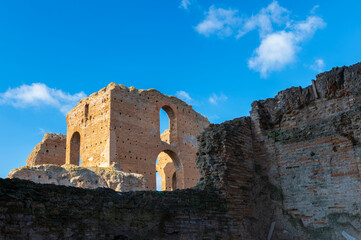 Ruins of the Imperial Villa dei Quintili, the thermal baths and the caldarium on the Via Appia in Rome, on a beautiful day of blue sky a suggestive panoramic image of the brick building.