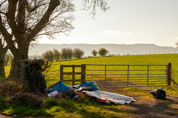 Illegal Fly Tipping by a Farmers Gate on a Quiet Rural Lane on a Sunny Day with Beautiful Views.
