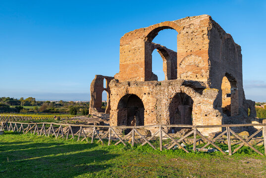 Imposing remains of the Villa dei Quintili, Rome, the thermal baths, a suggestive panoramic of the frigidarium with the blue sky, clouds and shadows on the green lawn. Appia Antica.