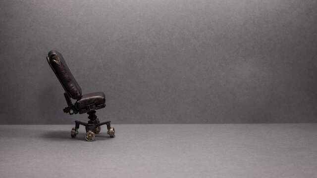 Comfortable black leather swivel office chair on a gray background. Cozy expensive place of work of the director or business leader. Copy space for text