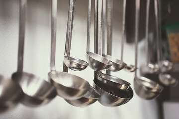 A view of several metal ladles hanging in a kitchen setting.