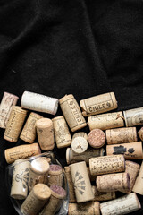 Bunch of wine corks and a glass over a black blanket
