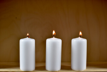 Fototapeta na wymiar Jasne, małe palące się świeczki na tle jasnej skleiki.