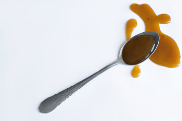 the drops of homemade sauce and a spoon on a white background