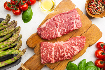 Raw Steak with green asparagus on white background, top view