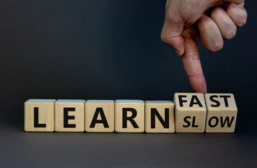 Learn slow or fast symbol. Businessman turns wooden cubes and changes words 'learn slow' to 'learn fast'. Beautiful grey background, copy space. Business and learn slow or fast concept.