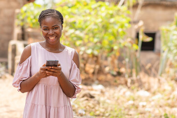 nigerian lady smiling, using her phone
