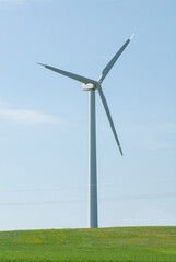 Fototapeta premium winnd tower rises from green field with powerlines