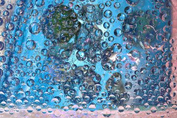 Transparent drops of water are located against a blue background with blue and green balls. Abstract fantasy. 3D render.
