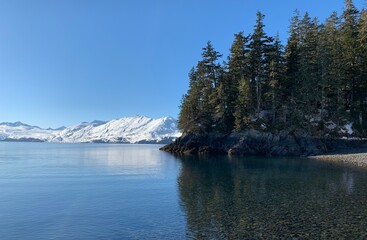 Large, Crystal Clear Lake in a Snow Covered Mountain Region with Tall Alpine Trees