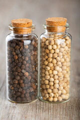 Two glass jars with black and whit pepper