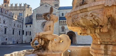 The empty fountain of Neptune with the Catholic Cathedral of San Vigilio on the Duomo square in the center of Trento. Sights Of Italy. © Tanya