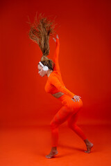 beautiful adult woman in a tracksuit on a red background in headphones 