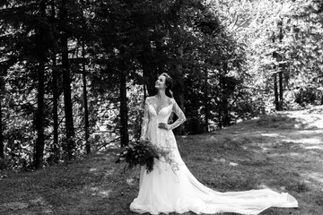 Fototapeta na wymiar The bride in a white beautiful long dress, holding a wedding bouquet