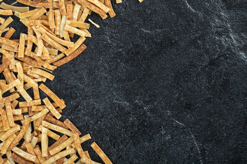 Uncooked pasta scattered on dark marble surface