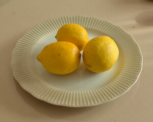 Three lemons on a plate. source of vitamin C.
