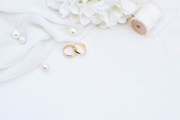 Two gold wedding rings with pearls , flower and ribbon on soft white background  Wedding background