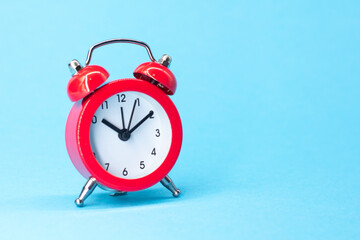 red round analog alarm clock isolated on blue background. time 10:10. space for text.