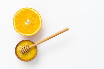 honey in a wooden bowl and orange on a white background.