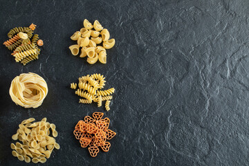 Assortment of raw pasta on dark background