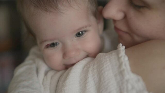 Mother kisses and hugs a 6 months old baby, maternal care and love. Close-up shot.