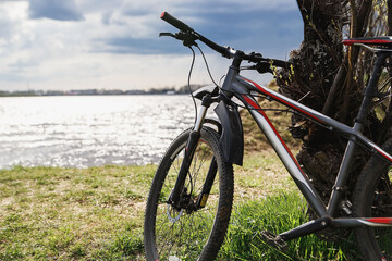 Fototapeta na wymiar Mountain bike stand on the river bank. Atmospheric dynamic light. Picnic.