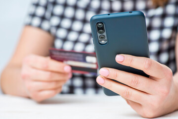 Womans hands hold credit card and use smartphone to shop online. Online shopping