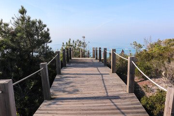 Obraz premium path made of wooden roasts, wooden bridge leading to the blue horizon over a sandy and overgrown cliff