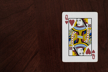 Queen of hearts card on a wood table, copy space on left