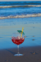 A delicious and refreshing cocktail on the sand of the beach near the waves.
