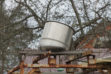 one gray metal barrel lies on the structure for the shower in the yard outside